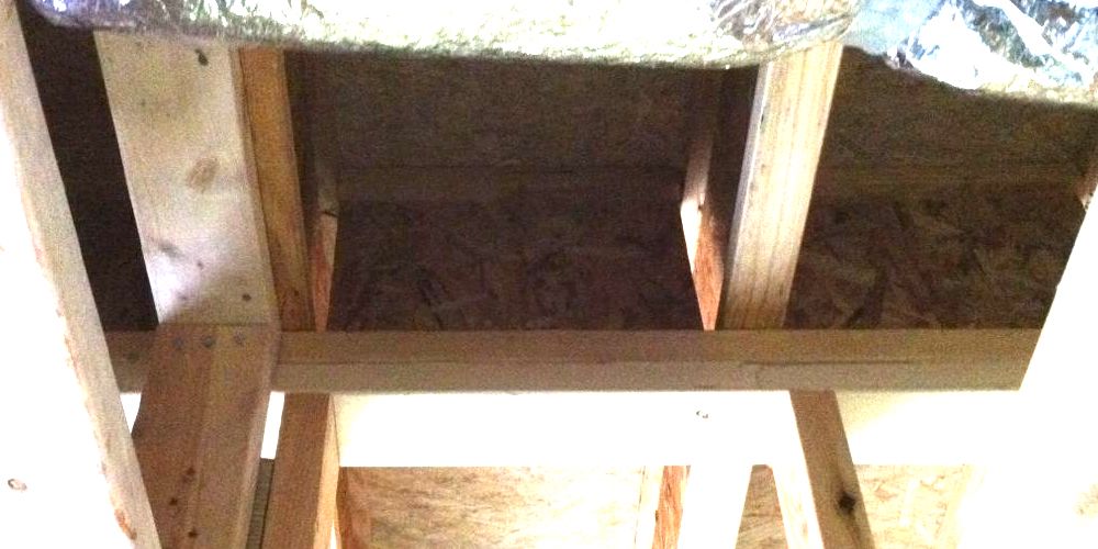 The blocking between floor joists in this wall between the garage and the living space has big unsealed gaps on the sides.